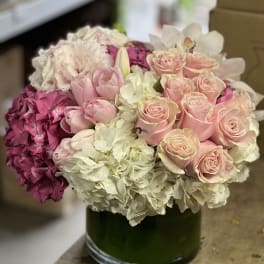 Pink roses and hydrangeas arranged in a green glass vase