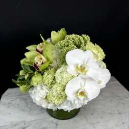 Green and white floral arrangement in a low round vase