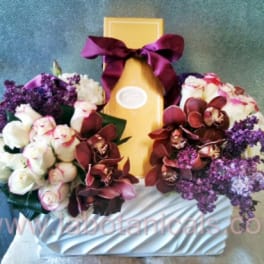 Two floral bouquets flank a gold gift box with a purple ribbon