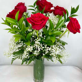 Red roses arranged in a clear glass vase with white filler flowers