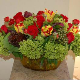 Mixed bouquet of red roses and yellow-red tulips in a glass bowl vase