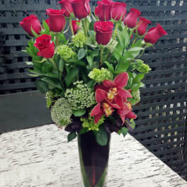 Red roses and pink orchids in a tall glass vase