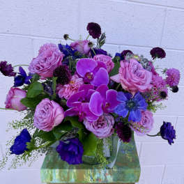 Bouquet of pink roses and purple orchids in a glass vase