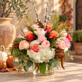 Mixed bouquet of roses and hydrangeas in a clear glass vase