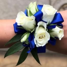 White rose wrist corsage with blue ribbon and green leaves