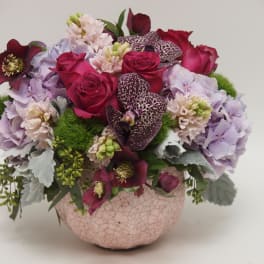 Pink and purple floral arrangement in a cracked ceramic bowl