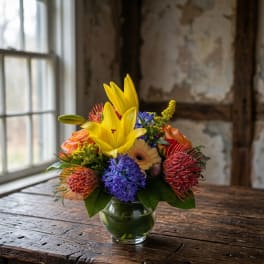 Mixed bouquet in a glass vase with yellow lilies and colorful blooms