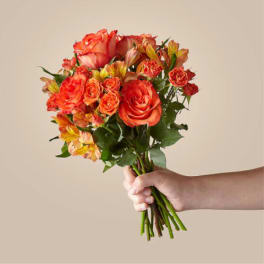 Handheld bouquet of orange roses and alstroemeria