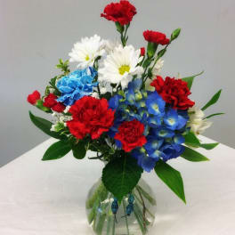 Colorful bouquet of carnations and daisies in a round glass vase