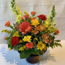 Colorful mixed flower arrangement in a brown glass vase