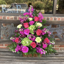 Pink and magenta floral arrangement in a wooden basket