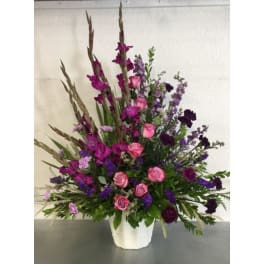 Tall purple and pink floral arrangement in a white vase