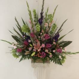 Tall floral arrangement with pink and purple roses in a basket