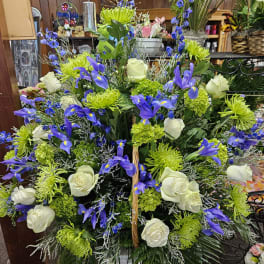 Tall blue iris, green mums, and white rose arrangement in a white pedestal vase