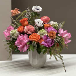 Mixed pink, orange, and white flowers arranged in a white vase