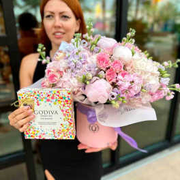 Pink and lavender flower arrangement in a round box with a chocolate gift box