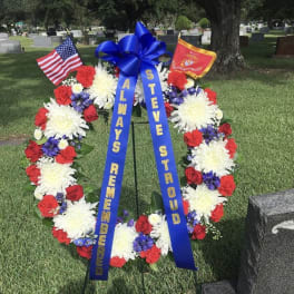 Patriotic funeral wreath with red, white, and blue flowers and ribbons