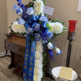 Standing funeral spray with white chrysanthemums, blue roses, and blue ribbons