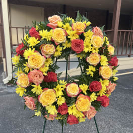 Circular wreath of yellow daisies and multicolored roses on a stand