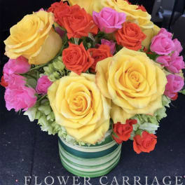 Bouquet of yellow, red, and pink roses in a striped vase