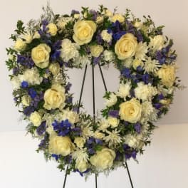 Heart-shaped floral wreath with cream roses, white blooms, and blue flowers