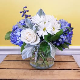 Blue and white flowers arranged in a clear glass vase