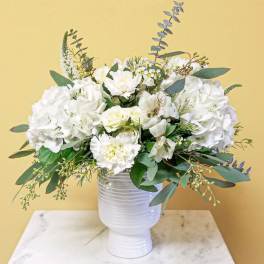 White floral arrangement in a white vase with eucalyptus