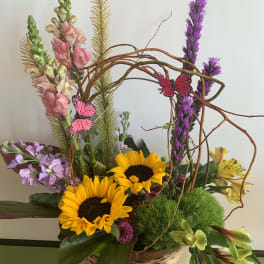 Basket arrangement with sunflowers, snapdragons, and purple flowers