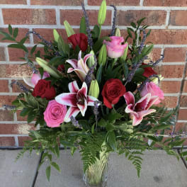 Mixed bouquet of pink and red roses with lilies in a glass vase