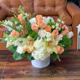 Peach and white floral arrangement in a white vase on a table