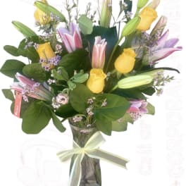 Bouquet of yellow roses and pink lilies in a glass vase