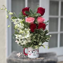 Bouquet of red and pink roses with white flowers in a Snoopy mug