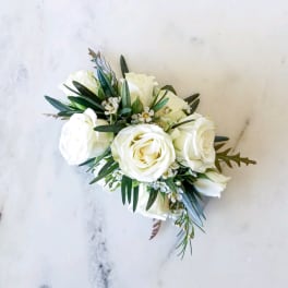 White rose bouquet with small white filler flowers and dark greenery