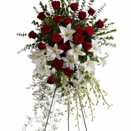 Standing spray of red roses, white lilies, and orchids on a metal easel