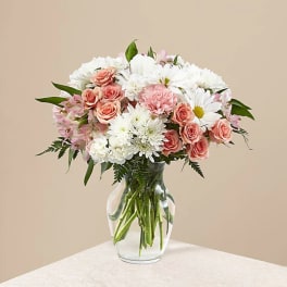 Pink roses and white daisies arranged in a clear glass vase