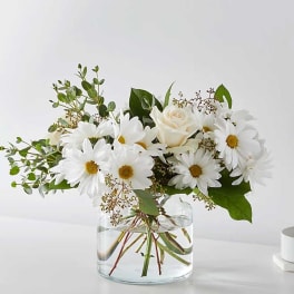 White daisies and a cream rose in a clear glass vase