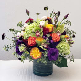 Mixed bouquet in a blue vase with roses, hydrangea, and orchids