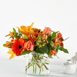Orange and peach mixed bouquet in a clear glass vase