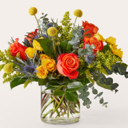 Bouquet of orange and yellow roses in a clear glass vase