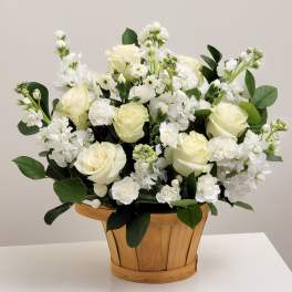 White roses and small white flowers in a wooden basket