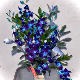 Purple and blue orchid arrangement in a clear glass vase