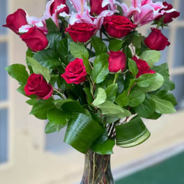 Bouquet of red roses and pink lilies in a clear glass vase