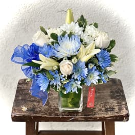 Blue and white mixed bouquet in a square glass vase with a ribbon