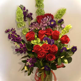 Bouquet of red roses and purple flowers in a glass vase