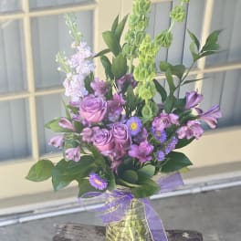 Mixed purple bouquet in a glass vase with a ribbon