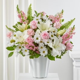 Pink roses and white lilies arranged in a white vase