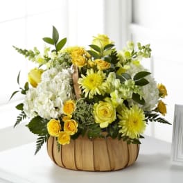 Yellow and white floral arrangement in a woven basket