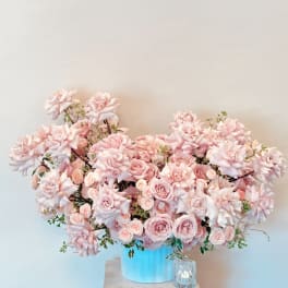 Large pink rose arrangement in a blue container on a pedestal