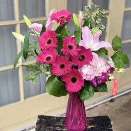 Pink gerberas and lilies in a magenta glass vase