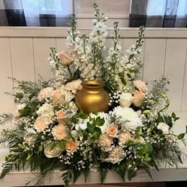 White and blush floral arrangement around a gold urn